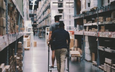 Workers navigating a warehouse layout with a cart