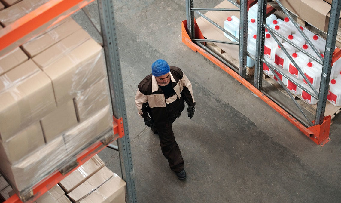 Warehouse worker walking through warehouse aisles