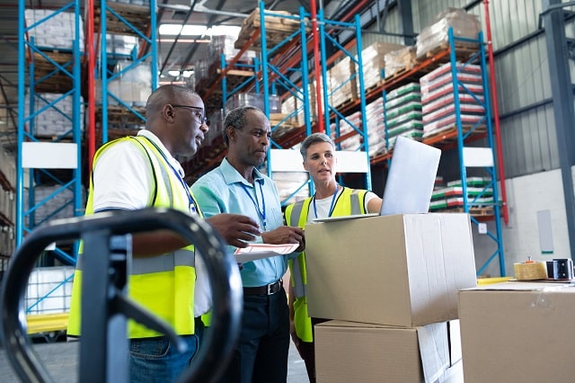 Warehouse workers reviewing warehousing KPIs on laptop