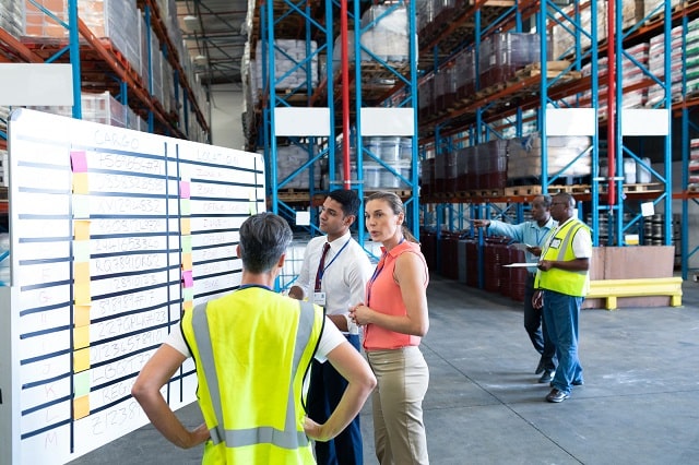 Warehouse staff talking in front of whiteboard