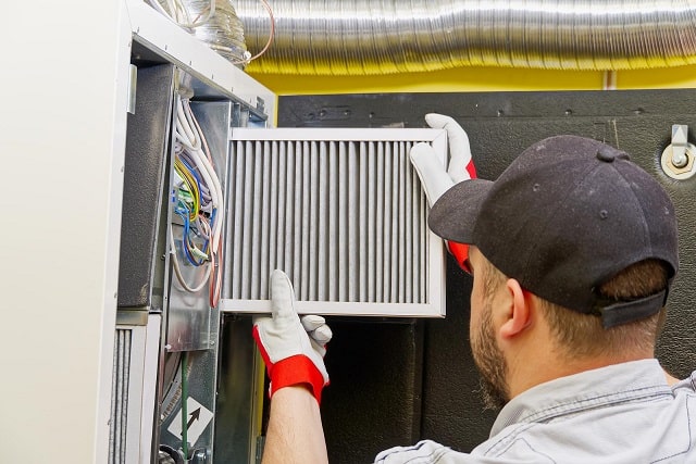 Technician replacing air filter in HVAC unit