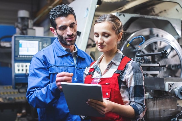 Workers discussing overall equipment effectiveness in a manufacturing plant