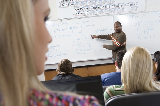 Professor lecturing a class in a brightly lit classroom