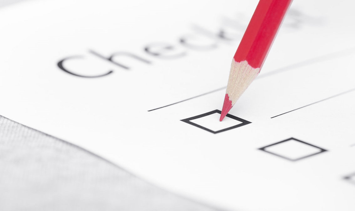 Red pencil checking off a checkbox on a checklist