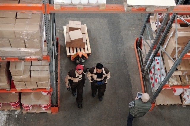 Overhead view of warehouse racks and worker pulling a cart