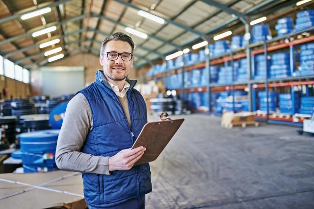 Man checking inventory in a warehouse on a clipboard