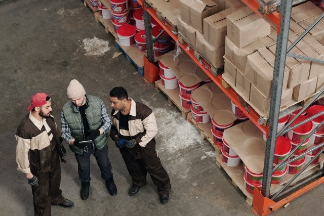 Warehouse workers discussing safety and compliance in an aisle