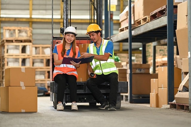 Workers checking newly arrived materials and storing on warehouse shelves 