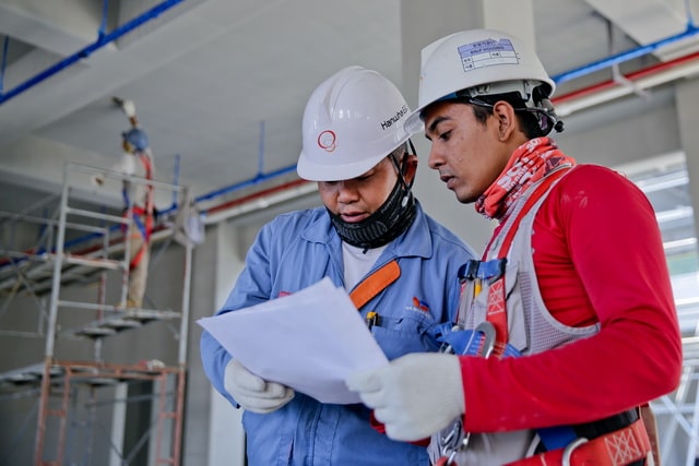 Two workers consulting on printed maintenance plans
