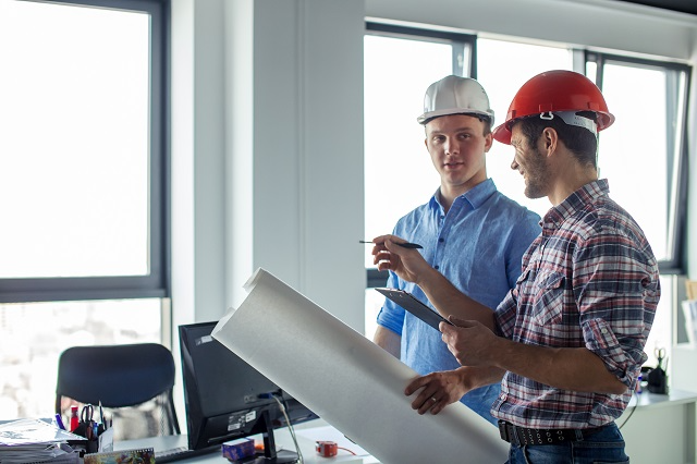 Facility manager discussing building regulations while reviewing facility plans