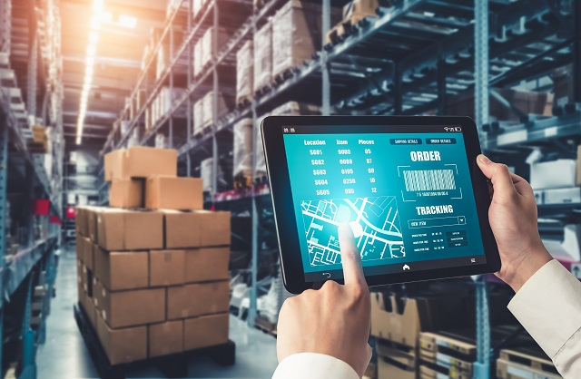 Person using warehouse control system on a tablet in a warehouse aisle