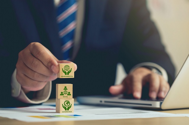 Business person stacking blocks representing Environmental Health and Safety (EHS)