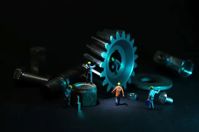 Small workmen repairing a large gear from a machine